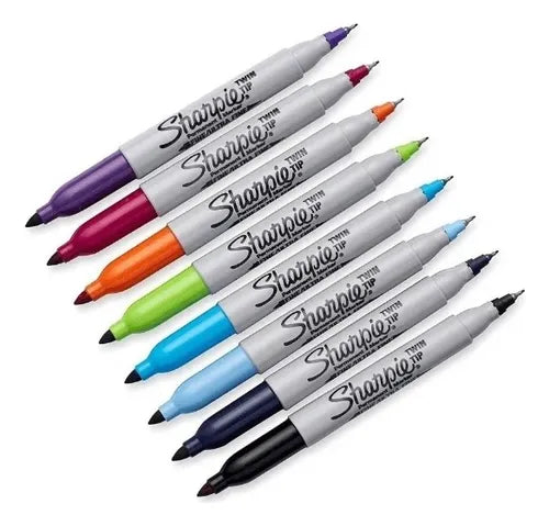 Ocho marcadores Sharpie doble punta (fina y biselada) alineados en tonos pastel: rosa, naranja, coral, amarillo, verde lima, turquesa, azul y morado, sobre fondo blanco.