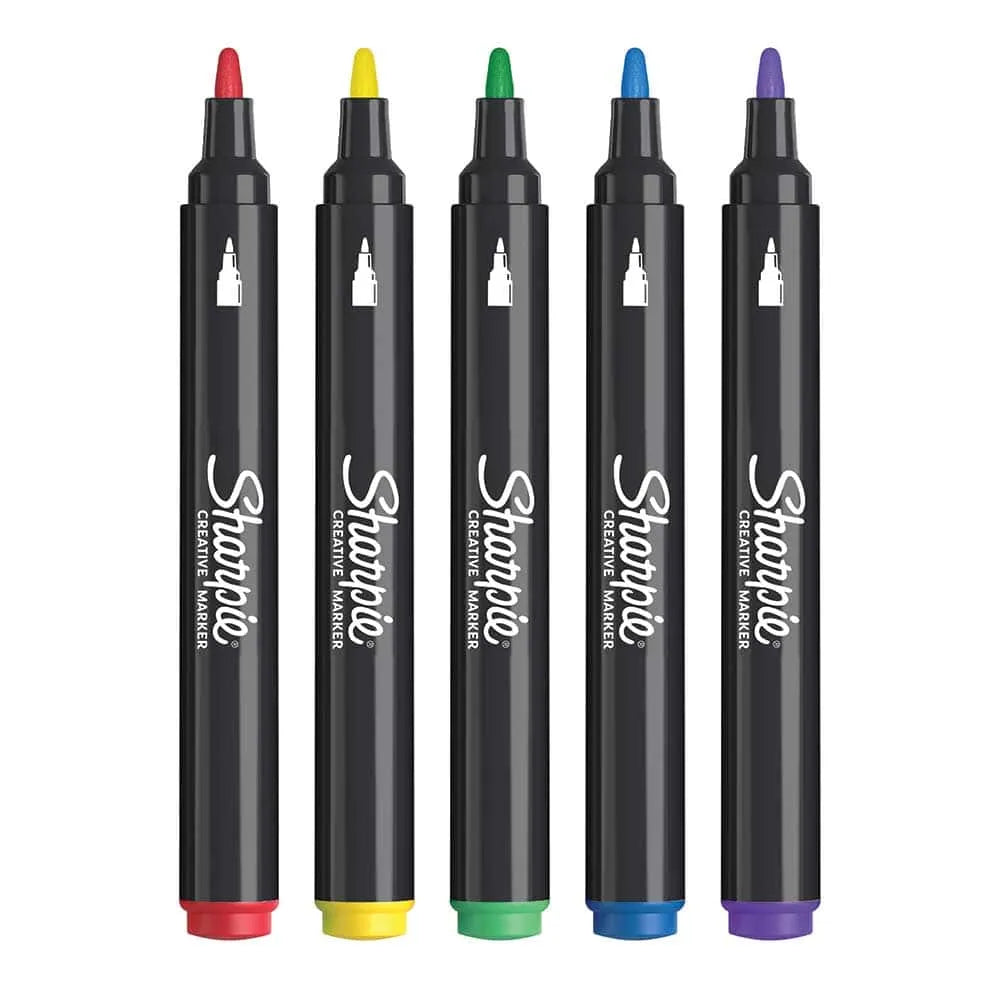 Cinco marcadores Sharpie acrílicos punta pincel en colores surtidos (rojo, amarillo, verde, azul, morado) alineados sobre fondo blanco.