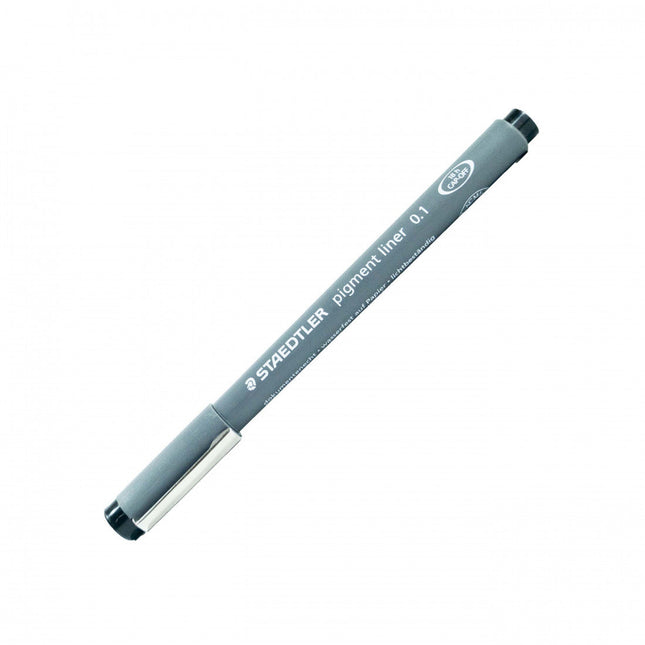 Rapidógrafo Staedtler negro 0.1 mm con punta metálica fina, cuerpo gris y capuchón, sobre papel de dibujo técnico.

