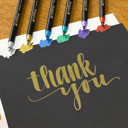 Set de 6 marcadores Edding punta pincel metalizados con colores brillantes y cubrientes, ideales para lettering y manualidades.