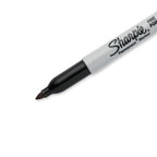 Cuatro marcadores Sharpie negros de punta fina con barril gris y tapas negras, alineados sobre fondo blanco.

