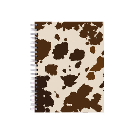 Cuaderno argollado Cow Print Toy de 5 materias con cubierta blanca y manchas negras tipo vaca, 150 hojas bond, argolla blanca visible y estilo juvenil.