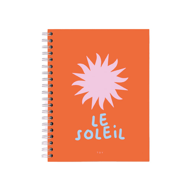 Cuaderno argollado grande Toy Le Soleil con portada naranja y sol gráfico rosado, tamaño 21,5×28 cm, 80 hojas bond, argollado metálico, con stickers y bolsillo interior.