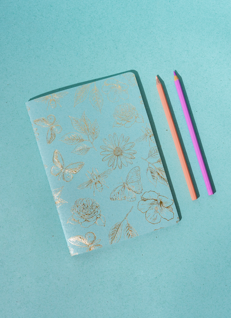 Libreta Econotas Alpen 15×21 cm azul con estampado de flores y mariposas en foil dorado y 32 hojas ecológicas cosidas en hilo.