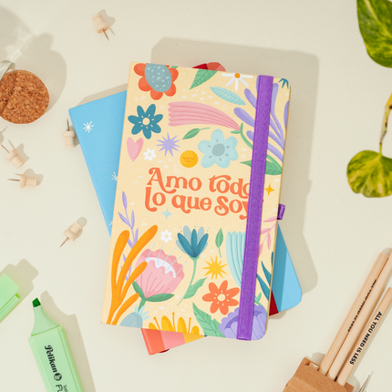 Sketchbook Alpen 12×20 cm con tapa dura floral y frase “Amo todo lo que soy”, banda elástica morada y 84 hojas blancas.