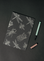 Libreta Econotas Alpen 15×21 cm color negro con ilustraciones de insectos en foil plateado y 32 hojas ecológicas cosidas en hilo.